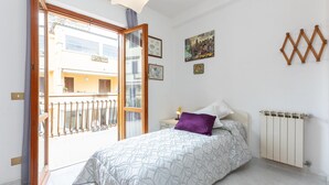 A bedroom with a bed, a nightstand, a radiator, and a balcony. - Apartment in Via Genova in Ladispoli a few steps from the sea and train station (Ladispoli)