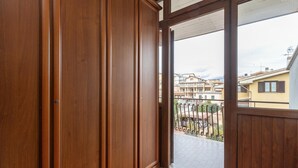 A wooden door leading to a balcony with a view of residential buildings. - Apartment in Via Genova in Ladispoli a few steps from the sea and train station (Ladispoli)