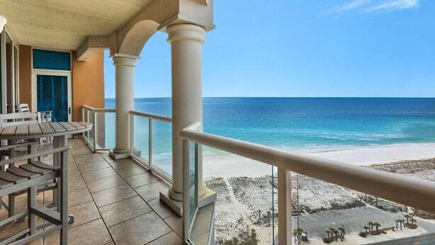 A balcony with a view of the beach and ocean.