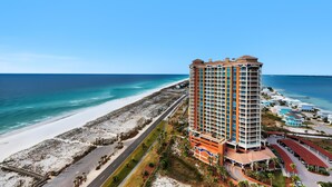 A high-rise hotel with multiple floors, a beach view, and a parking area.