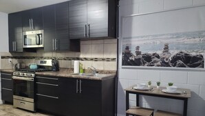 Une cuisine moderne avec des meubles de couleur sombre, des appareils électroménagers en acier inoxydable et un dosseret carrelé.