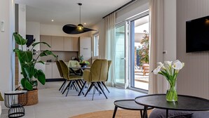 Een moderne woonkamer met een eetgedeelte, een grote plant en een bloemenvaas.