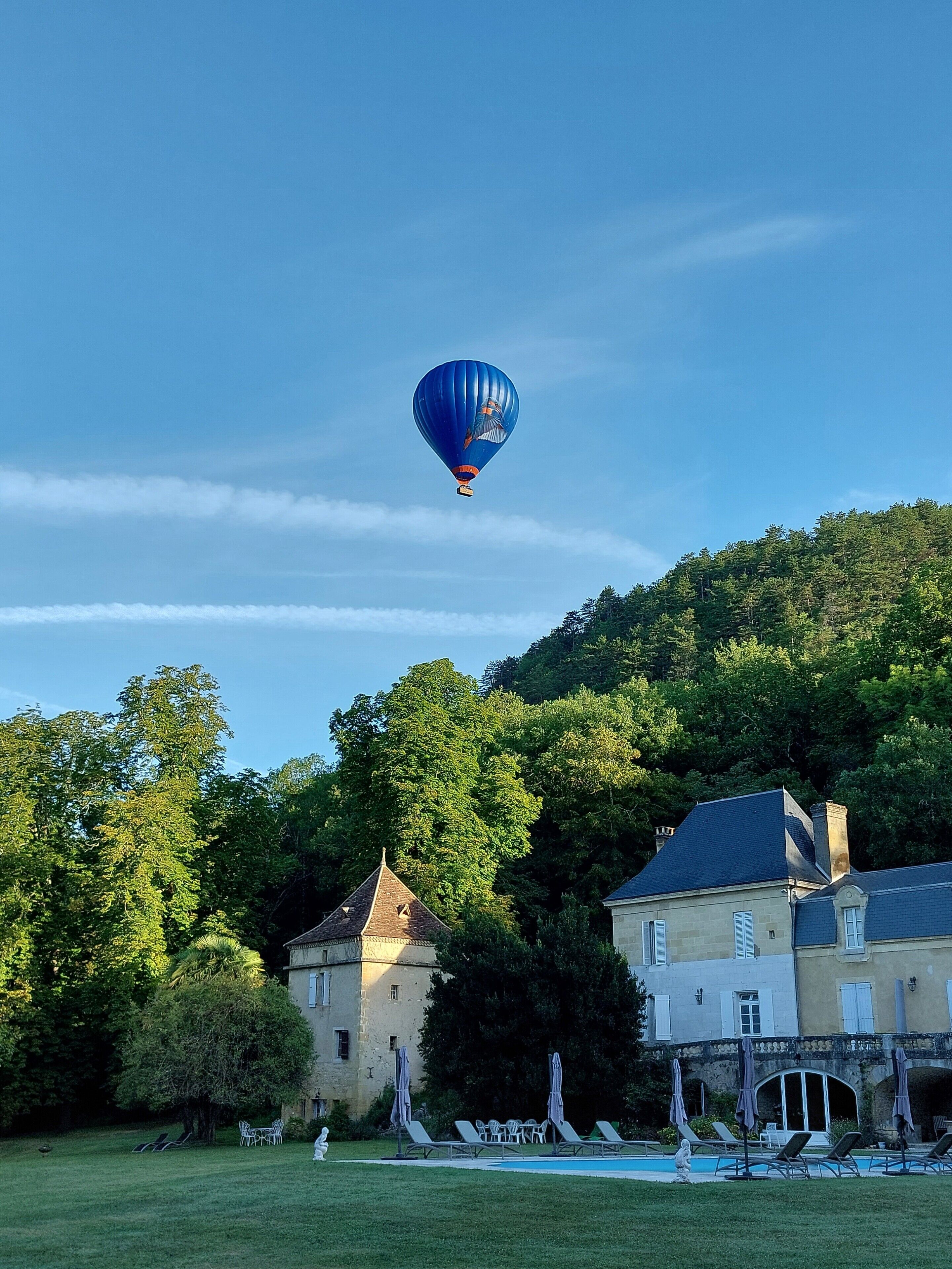 A hot air balloon, a swimming pool, and a building with a garden.