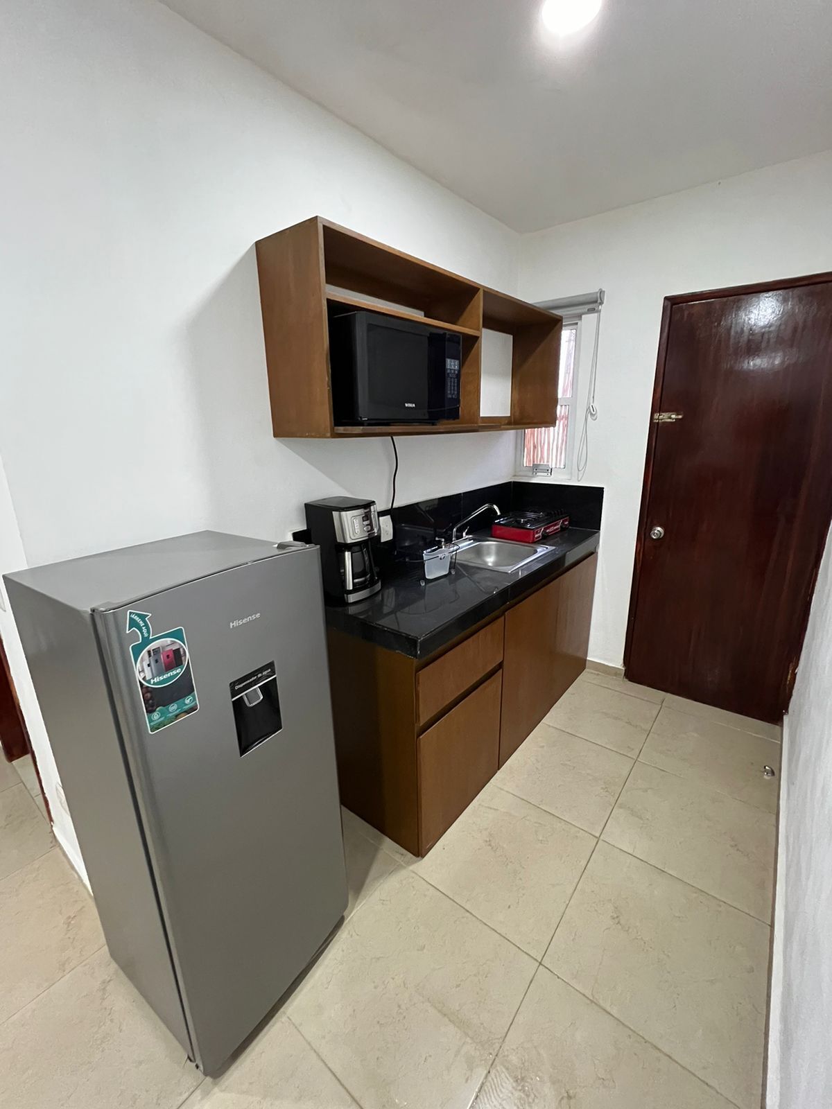 A compact kitchen with a refrigerator, microwave, and a coffee maker on the counter.