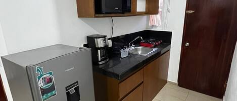 A compact kitchen with a refrigerator, microwave, and a coffee maker on the counter.
