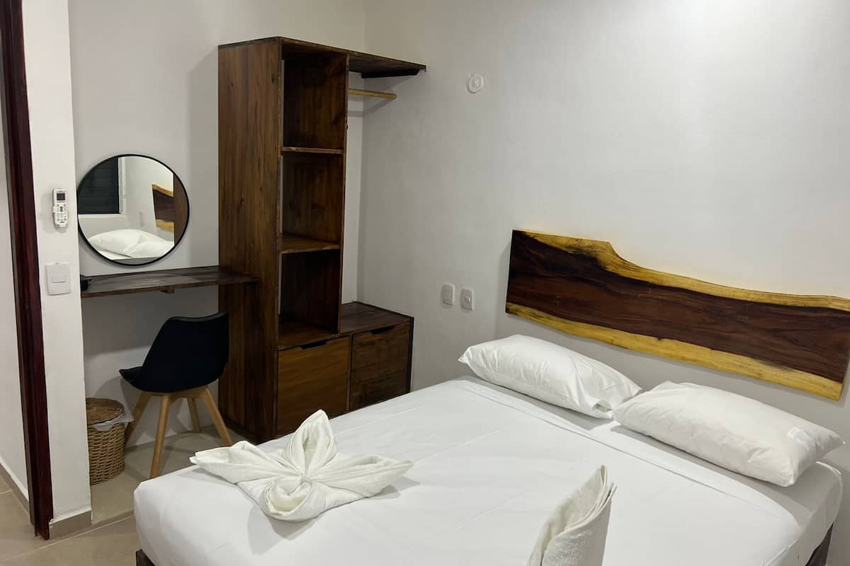A bedroom with a bed, a desk, a wardrobe, and a mirror.
