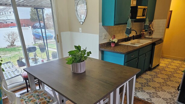Une cuisine avec des armoires de couleur turquoise, une table en bois et une plante en pot.