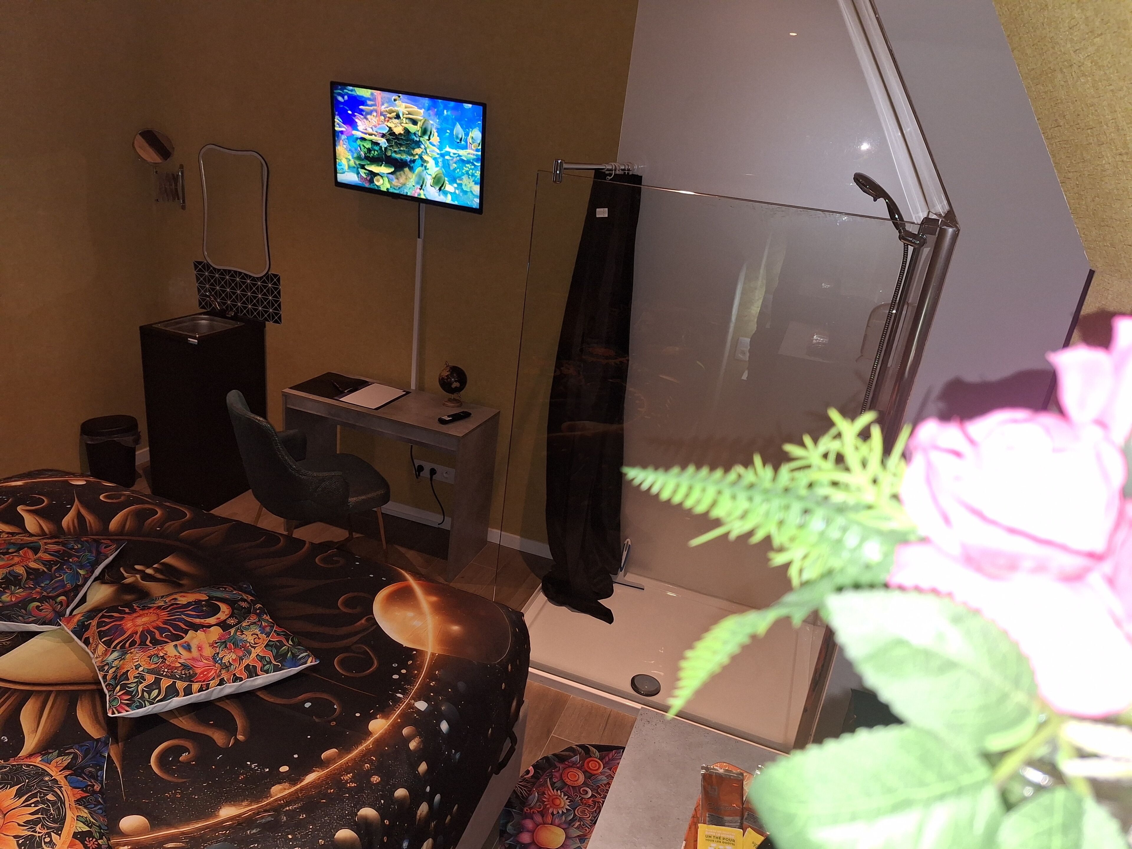 Een kamer met een bureau, stoel, televisie en een groot raam.