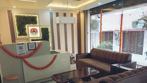 A reception area with a sofa, a glass-top table, and a decorative garland. - Hotel Shivalayam (Varanasi)