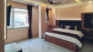 A bedroom with a bed, ceiling fan, and a window with curtains. - Hotel Shivalayam (Varanasi)