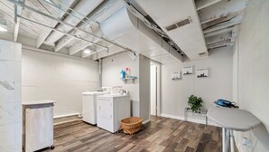 Une buanderie équipée d’un lave-linge, d’un étendoir et d’une petite table sur laquelle est posée une plante.