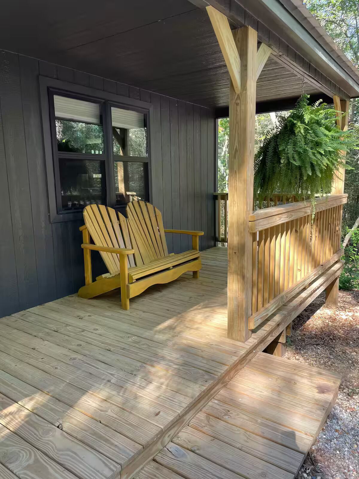 Une terrasse en bois avec deux fauteuils Adirondack et une fenêtre.