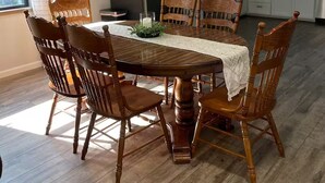 A dining area with a wooden table and chairs, a kitchen in the background, and a ceiling fan. - Quiet, Creekside Home with Rain Spa Shower, Unplug & Relax (Collins)