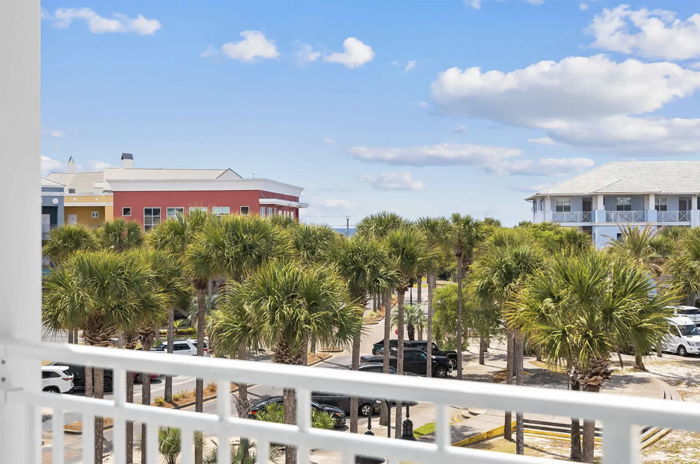 A view of a street with palm trees and buildings.