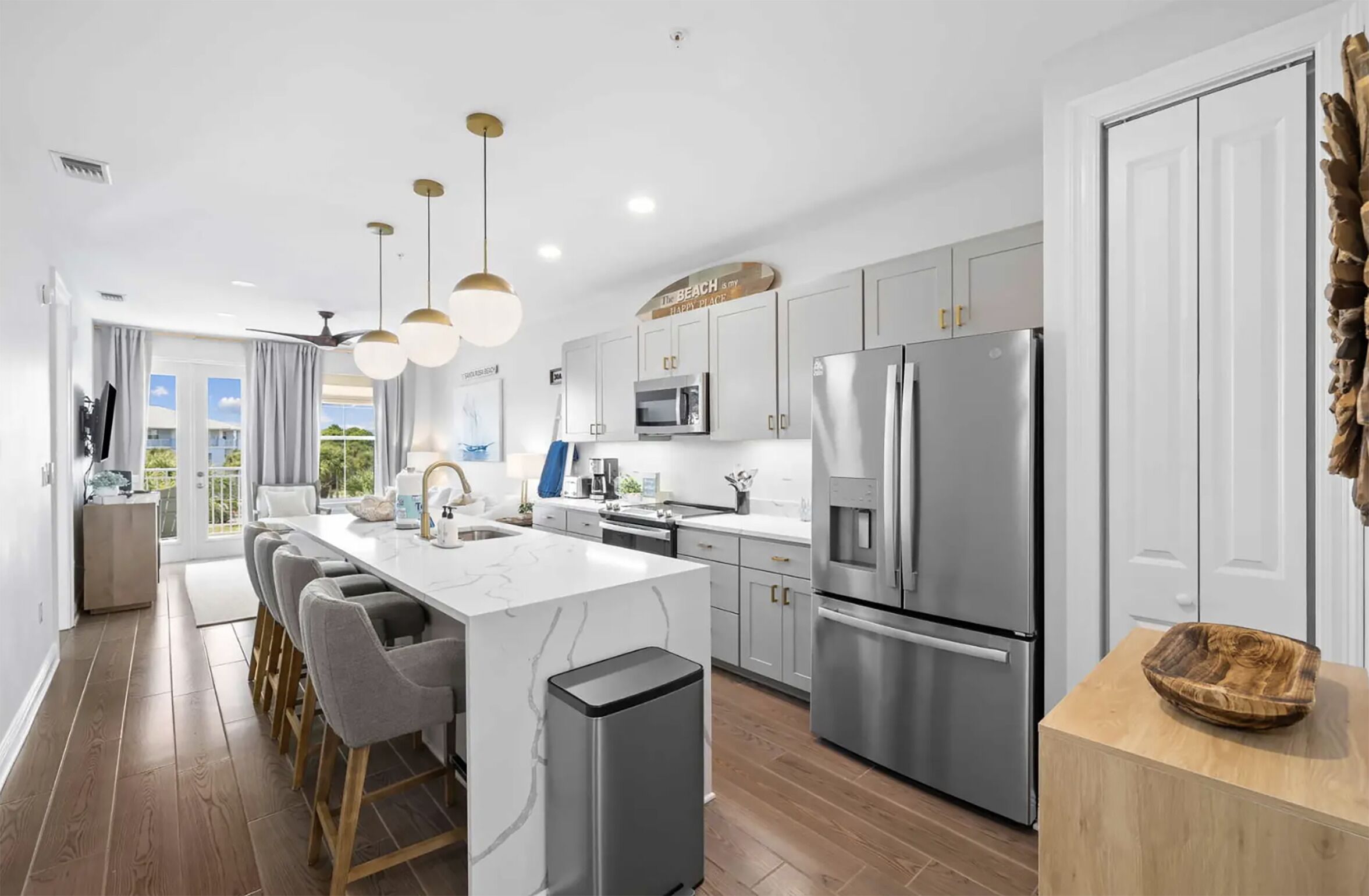 A modern kitchen with a central island, stainless steel appliances, and a view to the outside.