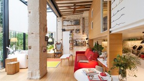 A modern living room with a red sofa, a white coffee table, and a bookshelf.