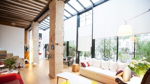 A spacious living area with a modern sofa, a wooden coffee table, and a red couch.