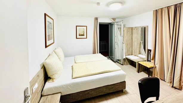 A hotel room with a bed, a chair, a desk, and a mirror. - Hotel Soad (Salach)