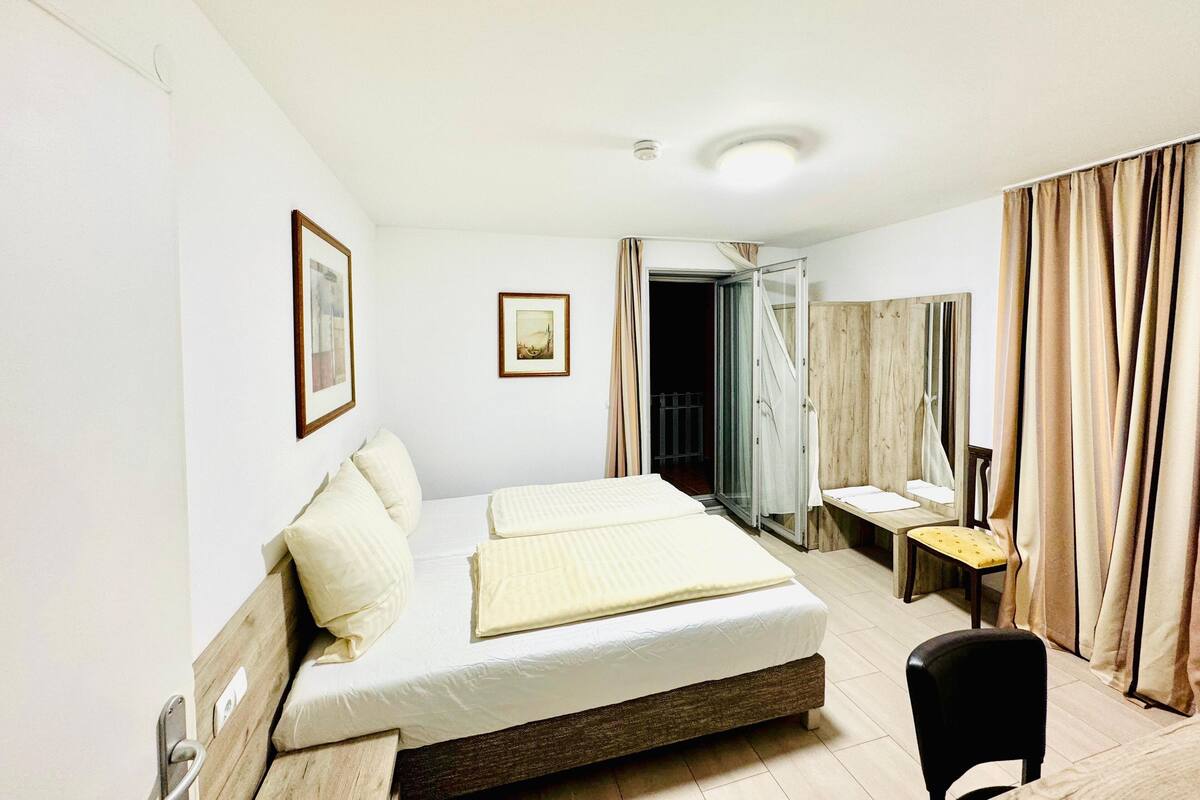 A hotel room with a bed, a chair, a desk, and a mirror.