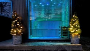 A modern glass structure with a metal railing, illuminated by blue and white lights. - Stunning Character Property with Hot tub (kendal)