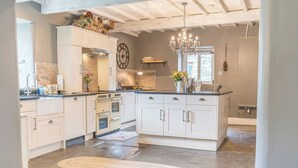A spacious kitchen with white cabinetry, a central island, a double oven, and a chandelier. - Stunning Character Property with Hot tub (kendal)