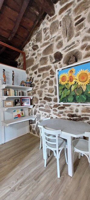 Cozy room with a stone wall, wooden beams, and a dining table for four.