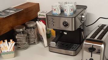 Een keuken met een koffieapparaat, een broodrooster en opslagpotten.
