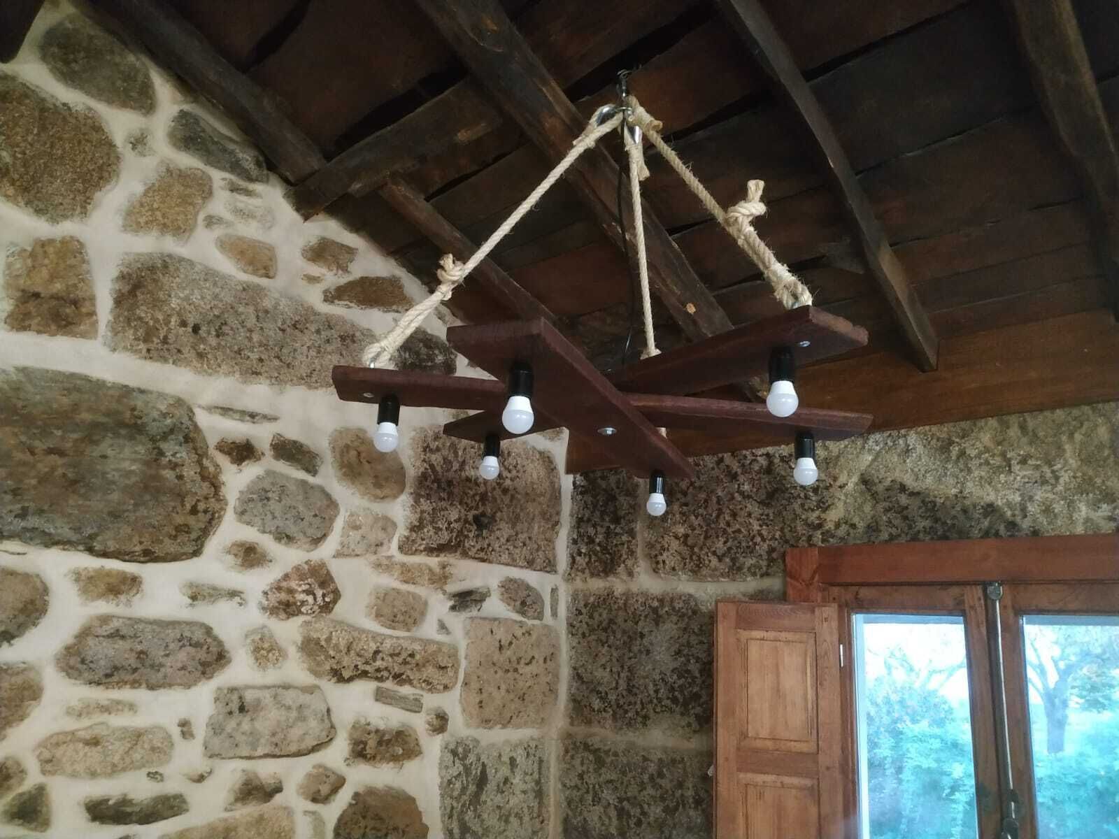 A rustic stone wall with a wooden ceiling and a rustic chandelier.