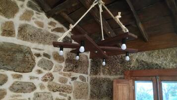 A rustic stone wall with a wooden ceiling and a rustic chandelier.