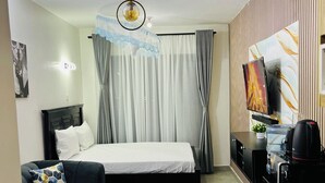 A modern hotel room with a bed, a sofa, a coffee machine, and a TV.