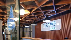 A reception desk with a sign reading "TSAVO FEDHA" in a modern interior with wooden paneling and glass partitions.