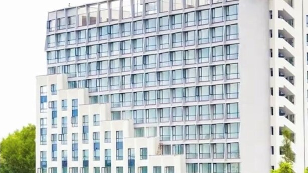 A multi-story hotel with a modern design, featuring a grid of windows and balconies.