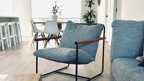Un moderno salón con un sillón tapizado gris, un sofá a juego y una alfombra estampada.