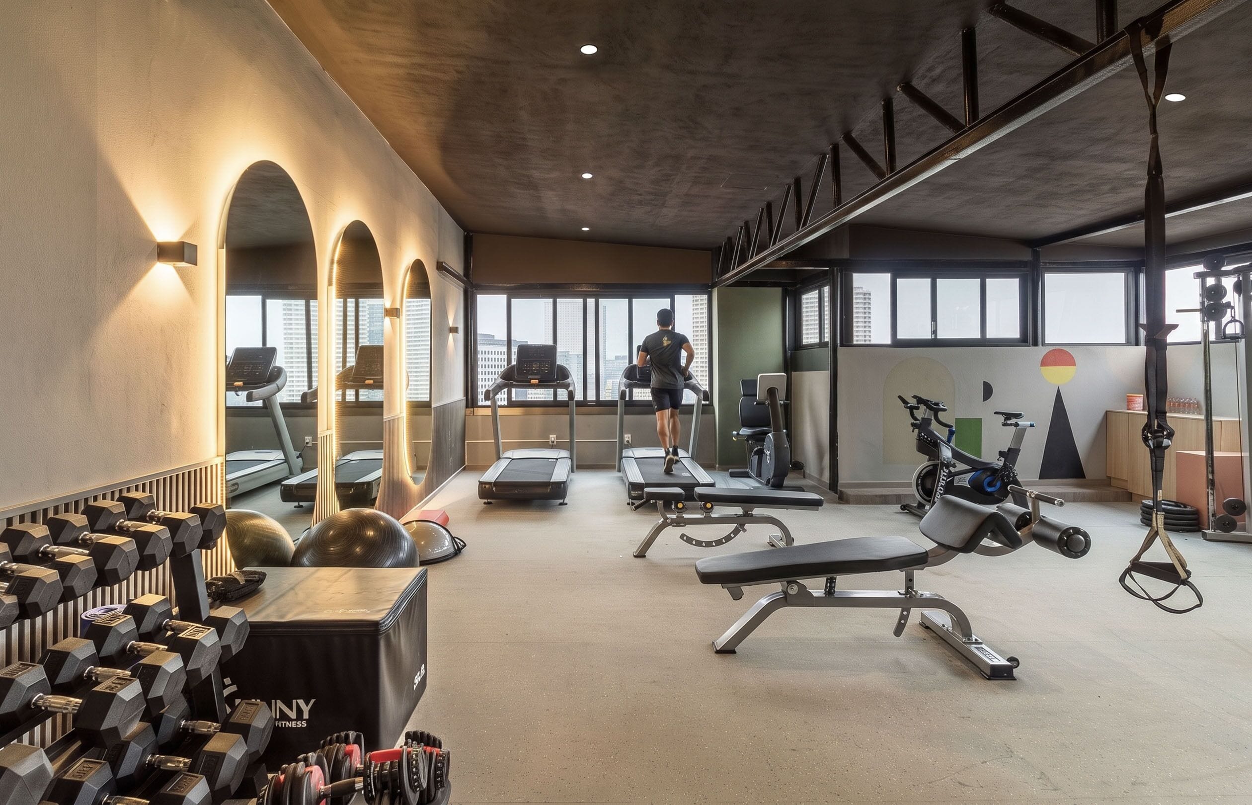 Una palestra con tapis roulant, panche per pesi e manubri.