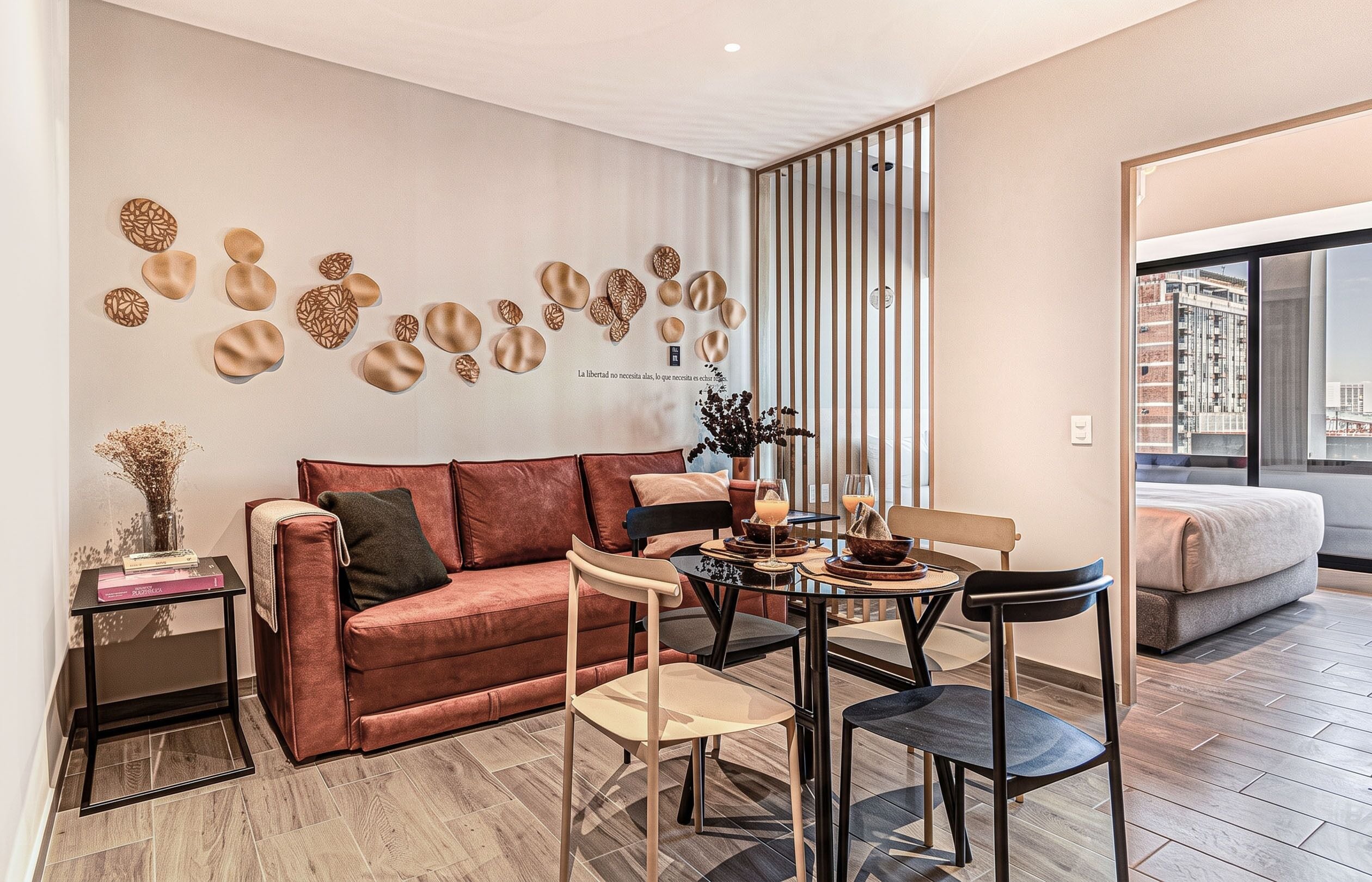Un salon moderne comprenant un canapé, des fauteuils, une table basse, des éléments décoratifs muraux et une vue sur la ville grâce à de grandes fenêtres.