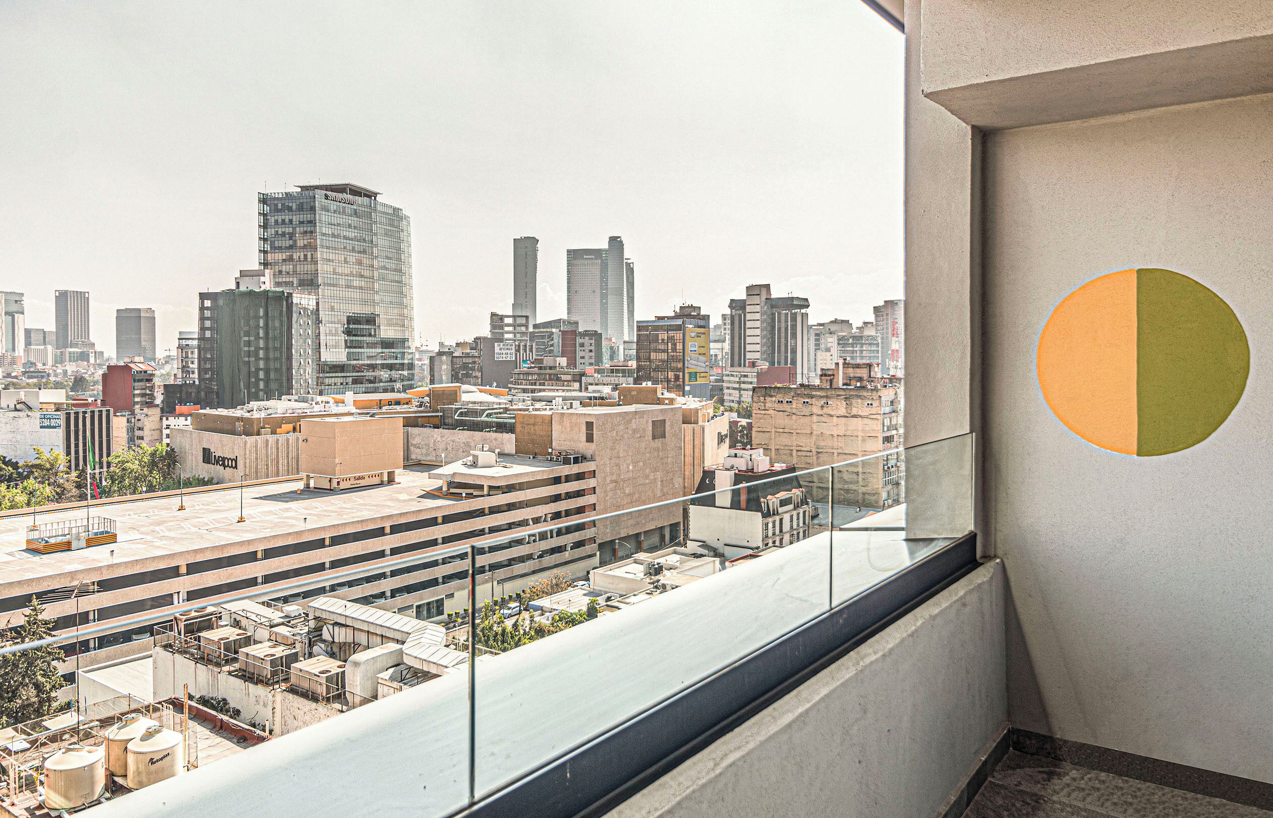 A high-rise building with a view of a cityscape, including various buildings and a large circular design on the wall.