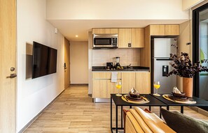 Una cocina moderna con armarios de madera, microondas integrado y refrigerador de acero inoxidable.