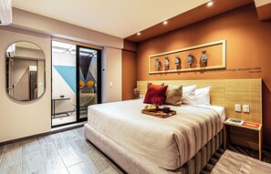 A hotel room with a bed, a breakfast tray, a wall-mounted vase display, and a sliding glass door leading to a balcony.