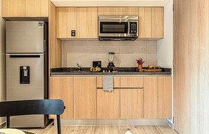 Una cocina compacta con refrigerador, microondas y licuadora sobre la encimera.