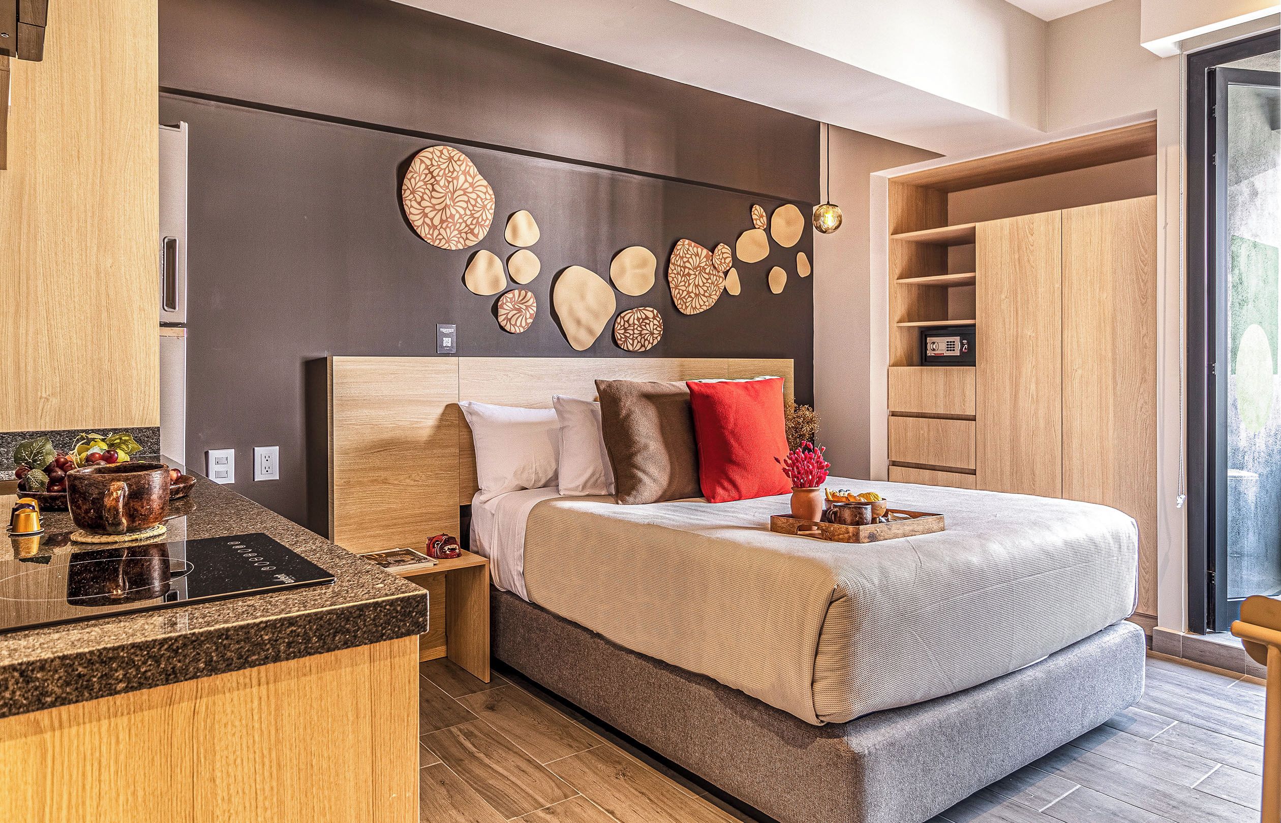 A modern bedroom with a bed, bedside tables, a built-in wardrobe, and a decorative wall.