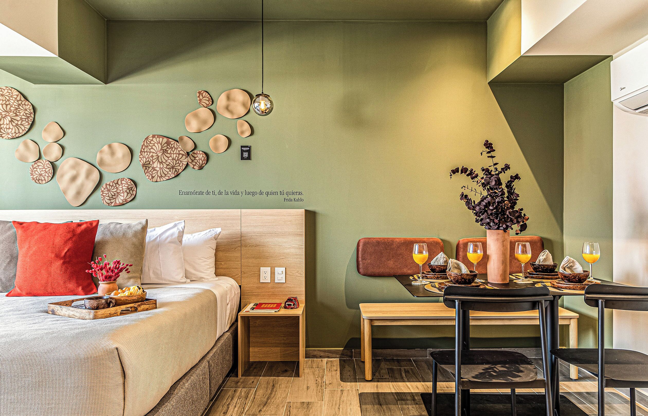 Habitación de hotel moderna con cama, mesita de noche y zona de comedor con una mesa para dos.