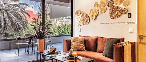 A modern living room with a large window, a sofa, a coffee table, and decorative wall art.