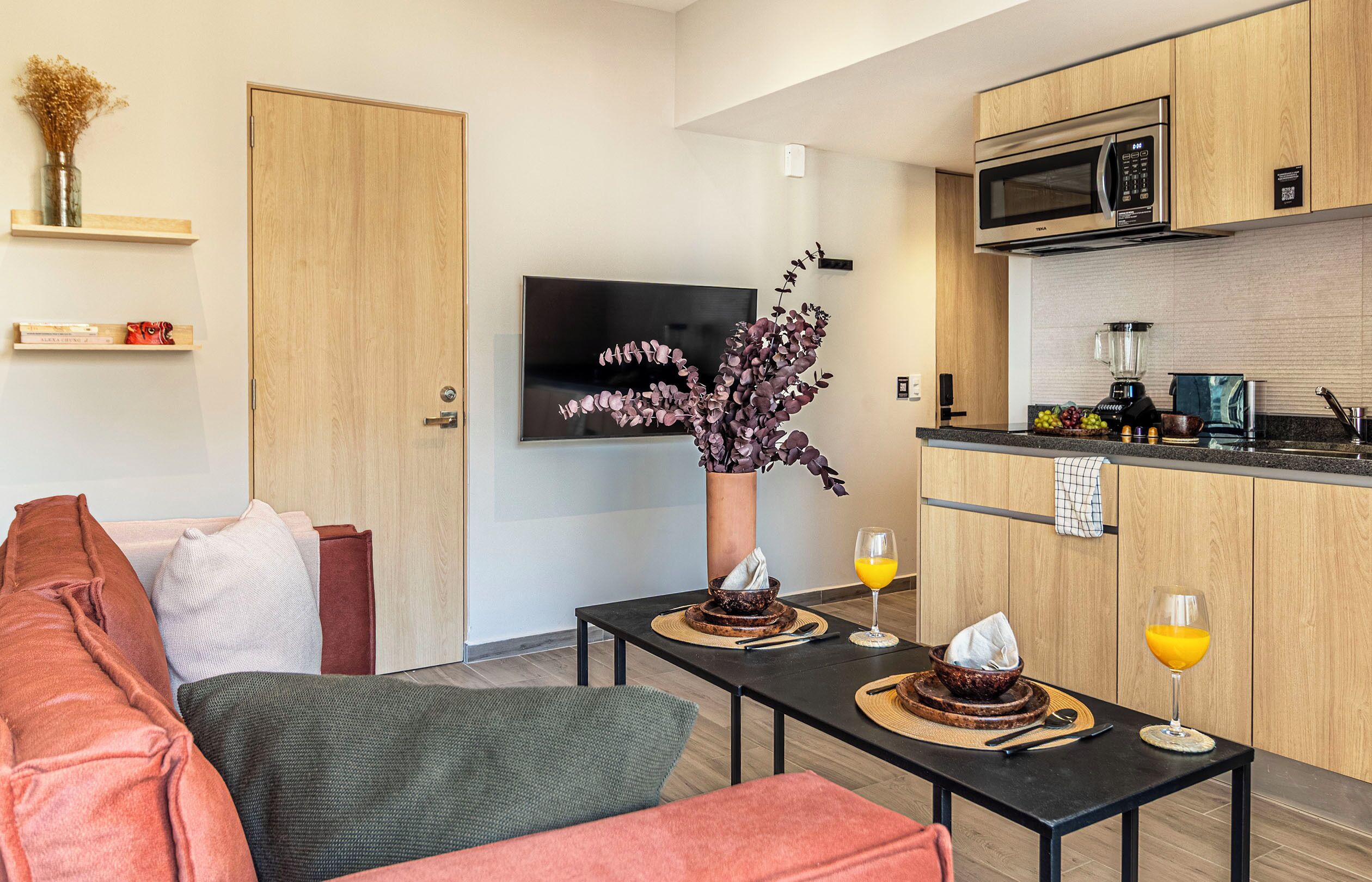 Une cuisine moderne avec des meubles en bois, un four à micro-ondes et un téléviseur fixé au mur.