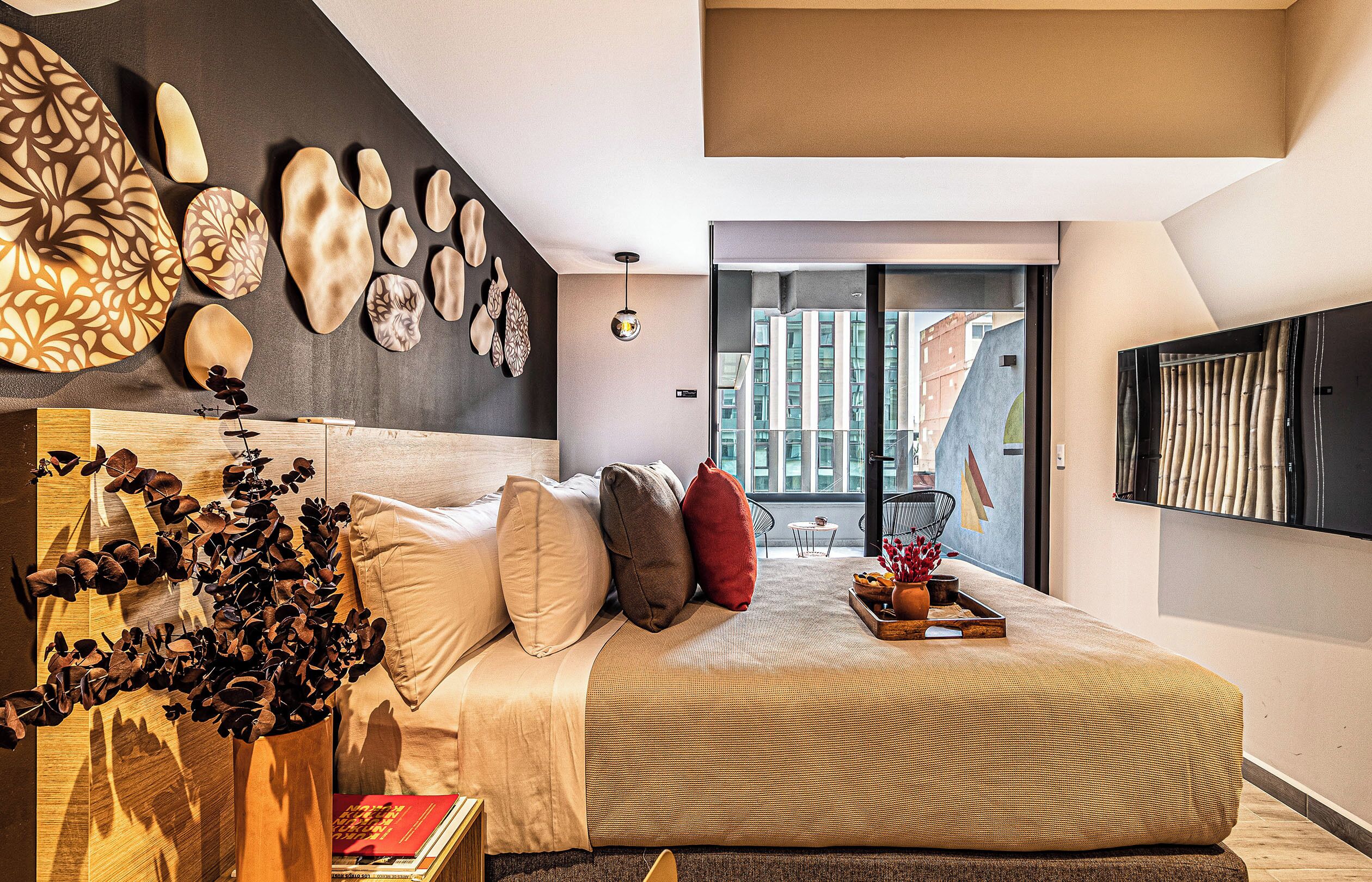 Un dormitorio moderno con una cama grande, un diseño decorativo en la pared, vistas de la ciudad y un televisor de pantalla plana.