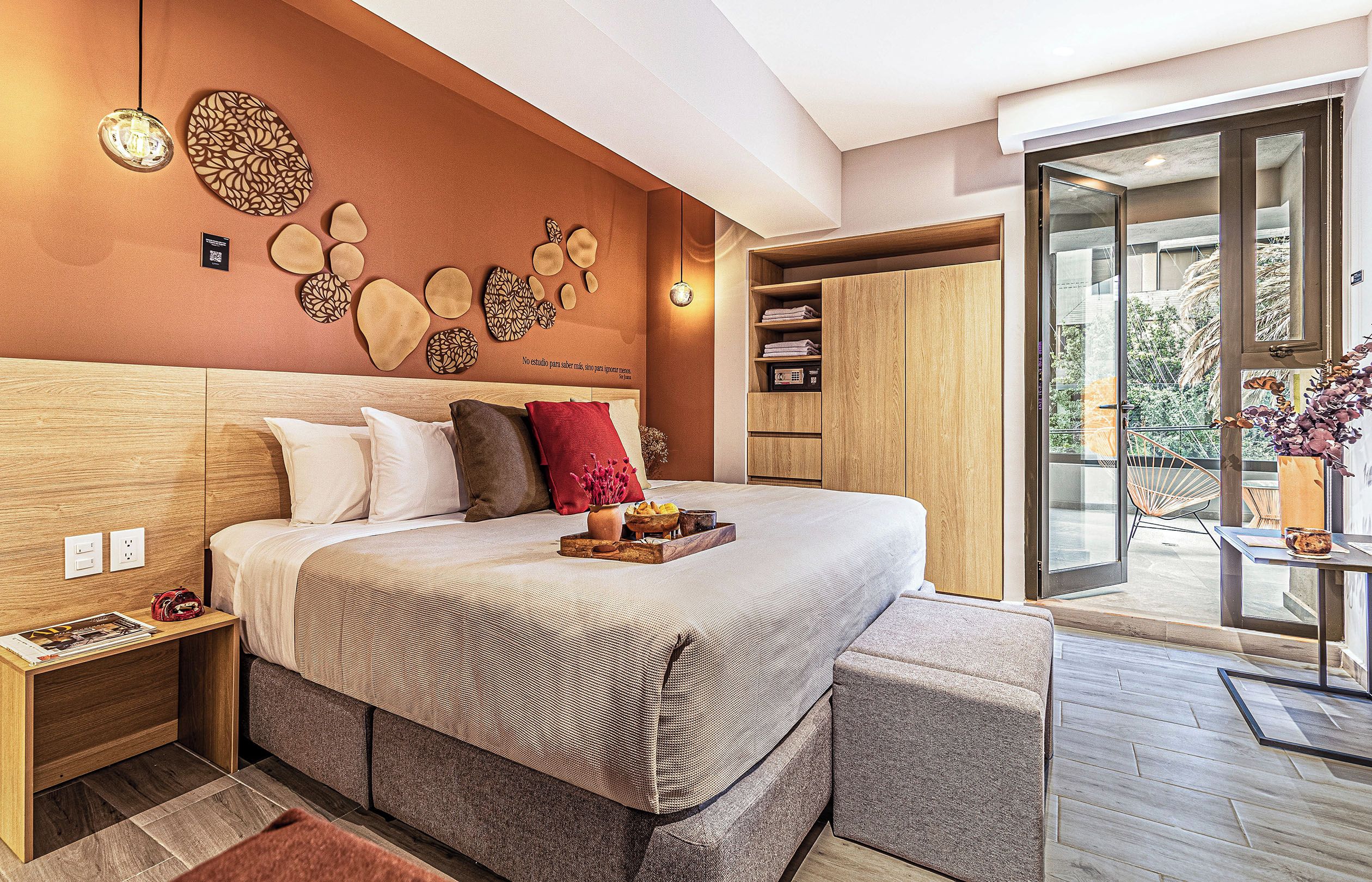 A modern bedroom with a large bed, bedside tables, a wardrobe, and a balcony with a view.