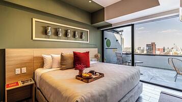 A modern bedroom with a city view, a bed with a wooden headboard, a bedside table, and a tray with snacks.
