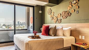 A modern bedroom with a large bed, a city view, and decorative wall art.