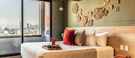 A modern bedroom with a large bed, a city view, and decorative wall art.