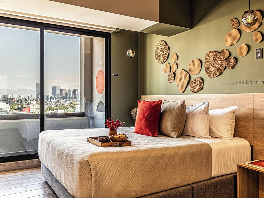 Un dormitorio moderno con una cama grande, vistas a la ciudad y decoración mural.