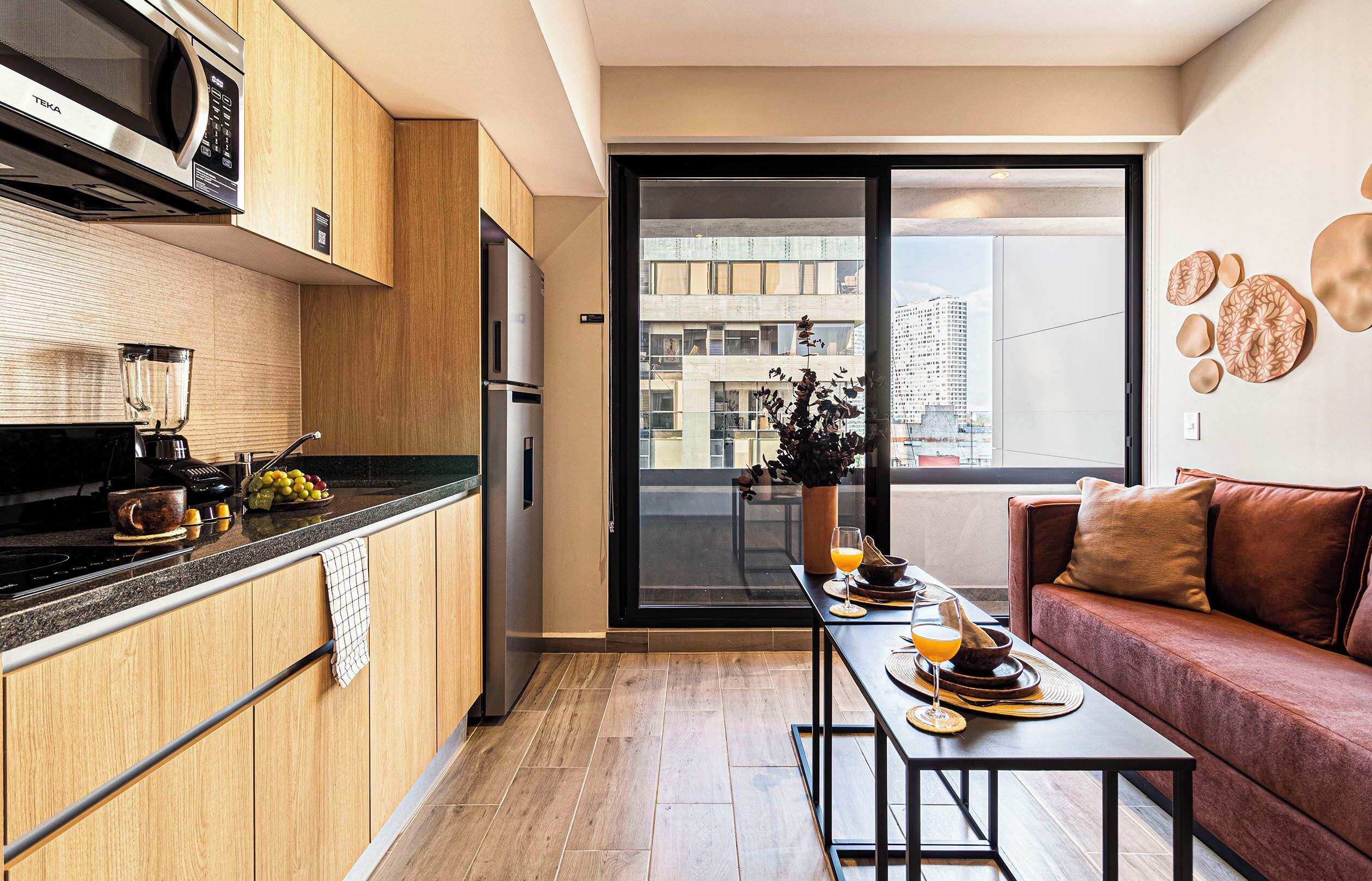 A modern kitchen with wooden cabinets, a built-in microwave, and a dining area with a table set for two.